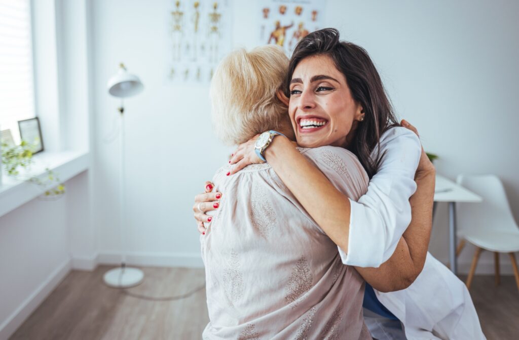 A grinning adult embraces their older parent, happy to visit their assisted living apartment for the first time
